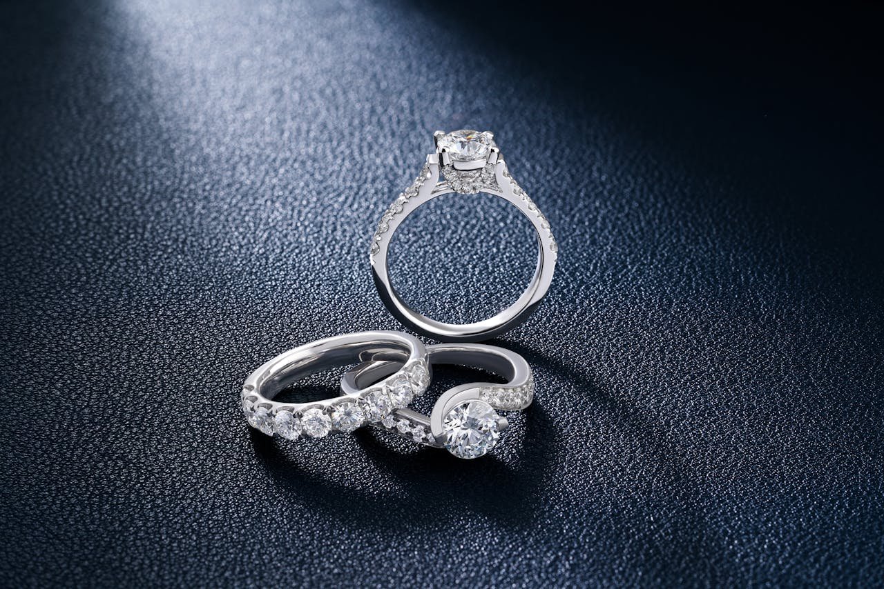 services-03 Close-up of luxurious diamond engagement and wedding rings on a textured surface, showcasing elegance and craftsmanship.