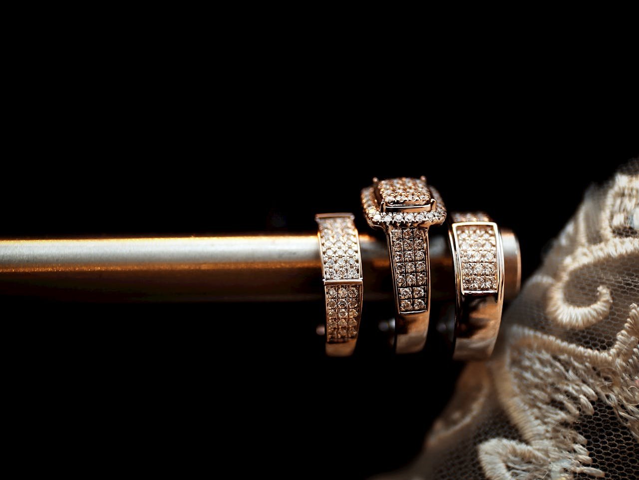 services-02 Close-up of luxury diamond wedding rings elegantly arranged with delicate lace in the background.