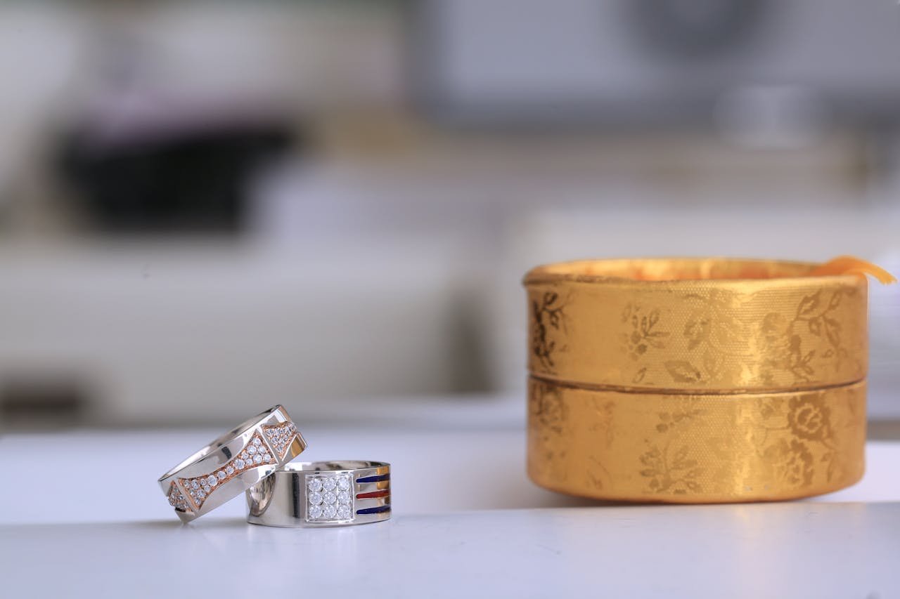 services-01 Close-up of silver wedding rings with diamonds next to a gold jeweler's box, perfect for elegant presentations.