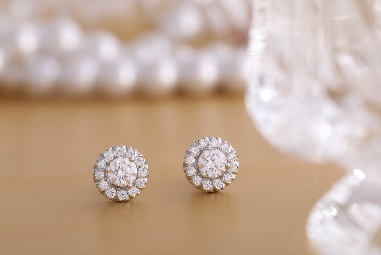 about-01 Close-up of round diamond earrings on a gold background, showcasing luxury and elegance.