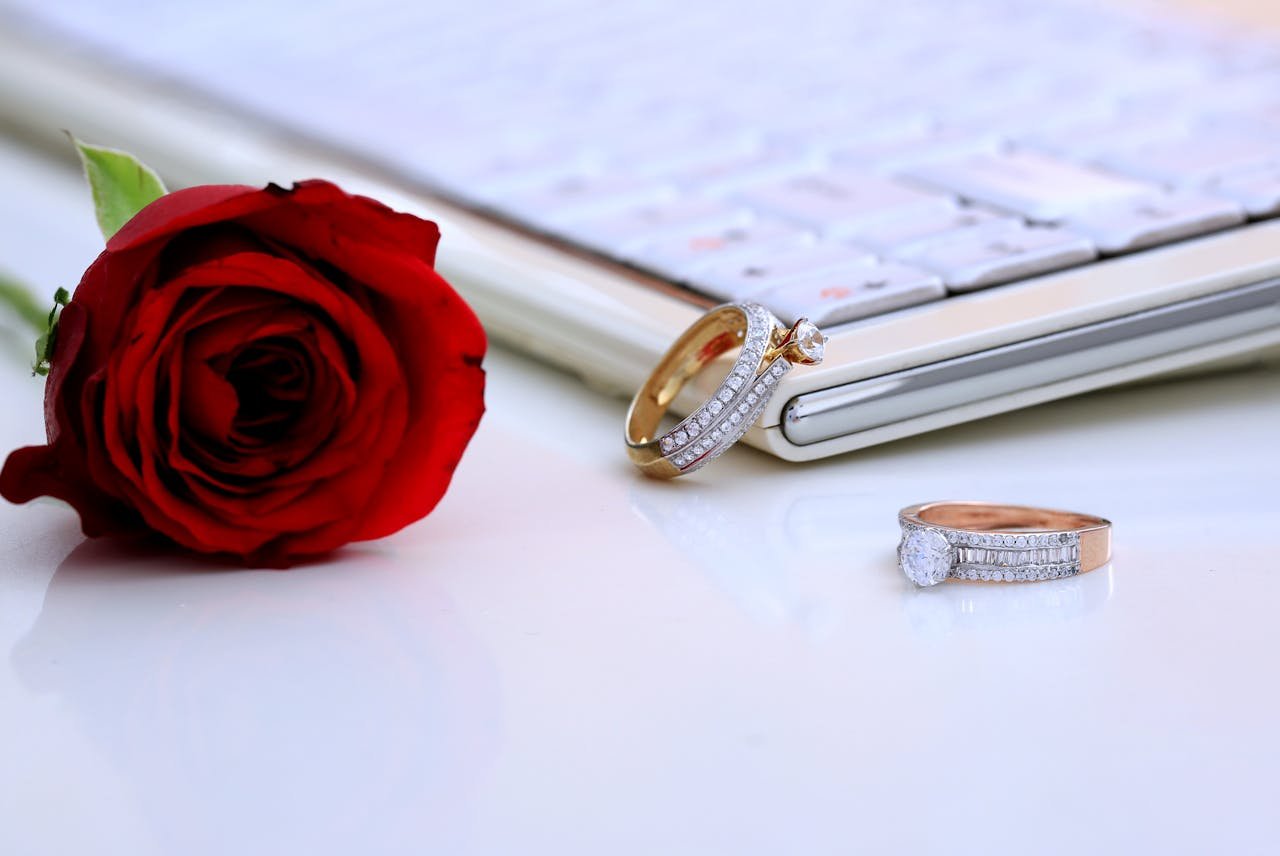 hero-img-02 Elegant diamond rings and a red rose displayed on a clean white surface, symbolizing luxury and romance.